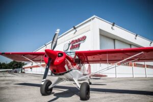 Prop plane positioned in front of the Grand Aire hangar